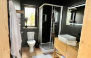 Bagno moderno con doccia, WC e mobili in legno nella Spa Design Cabin al Domaine des Feuilles, Francia.
