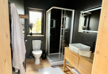 Bagno moderno con doccia, WC e mobili in legno nella Spa Design Cabin al Domaine des Feuilles, Francia.