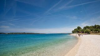 Spiaggia panoramica a Camping Brioni, Istria, Croazia, con acqua cristallina e alberi sullo sfondo.