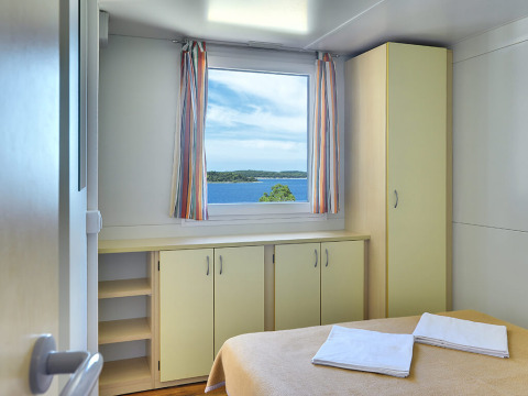 Lichte slaapkamer bij Brioni Home Seaside, Camping Brioni in Kroatië, met uitzicht op zee vanuit het raam.