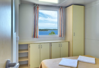 Chambre lumineuse au Brioni Home Seaside, Camping Brioni, Croatie, avec vue sur la mer par la fenêtre.