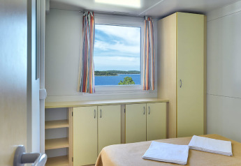 Chambre lumineuse au Brioni Home Seaside, Camping Brioni, Croatie, avec vue sur la mer par la fenêtre.