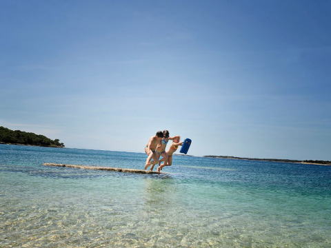 Due persone saltano insieme nell'acqua limpida al Camping Brioni, un villaggio in Istria, Croazia.