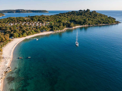 Vue aérienne de Camping Brioni en Istrie, Croatie, avec sa plage et son littoral boisé près d’une mer turquoise.