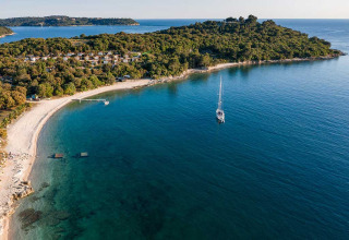 Luftaufnahme vom Camping Brioni Ferienpark in Istrien, Kroatien, mit klarem Wasser und bewaldeter Küste.