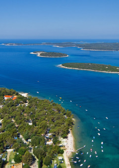 Foto aerea di Camping Brioni in Istria, Croazia, con spiagge, mare blu e isole verdi e lussureggianti.