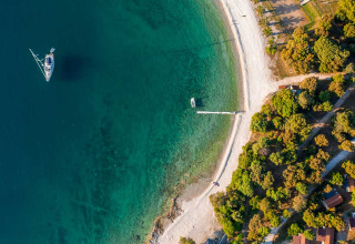 Aerial view of Camping Brioni holiday park in Istria, Croatia, featuring turquoise water, a boat, and beach.
