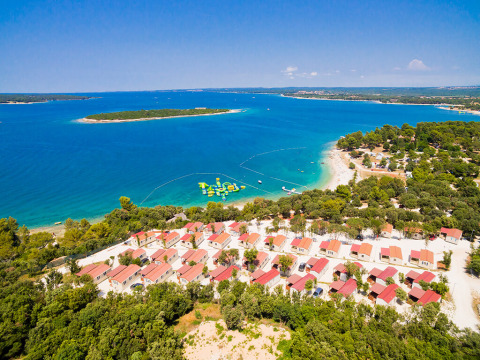 Aerial view of Camping Brioni holiday park in Istria, Croatia, with cabins, beach, and clear blue sea.