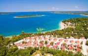 Aerial view of Camping Brioni holiday park in Istria, Croatia, with cabins, beach, and clear blue sea.