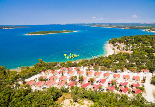 Aerial view of Camping Brioni holiday park in Istria, Croatia, with cabins, beach, and clear blue sea.