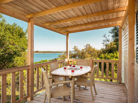 Terrasse en bois avec table à manger et chaises, vue sur la mer, Brioni Superior Home Seaside, Camping Brioni, Croatie.