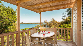 Wooden terrace with dining table and chairs, sea view and greenery, Brioni Superior Home Seaside at Camping Brioni, Croatia.