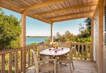 Terrazza in legno con tavolo da pranzo e sedie, vista mare e verde, Brioni Superior Home Seaside, Camping Brioni, Croazia.