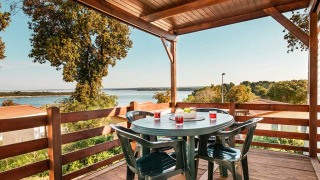 Vista desde el chalet Brioni Home Seaside en Camping Brioni, Croacia, con mesa y sillas en terraza cubierta.