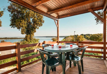 Zicht vanop Brioni Home Seaside chalet bij Camping Brioni, Kroatië, met tafel en stoelen op overdekt terras.