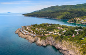 Aerial view of Valamar Camping Marina on a rocky coast in Istria, Croatia, surrounded by lush greenery.