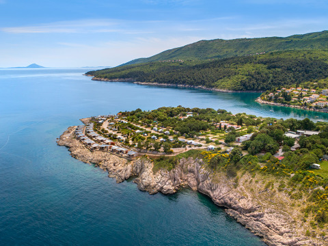 Aerial view of Valamar Camping Marina on a rocky coast in Istria, Croatia, surrounded by lush greenery.