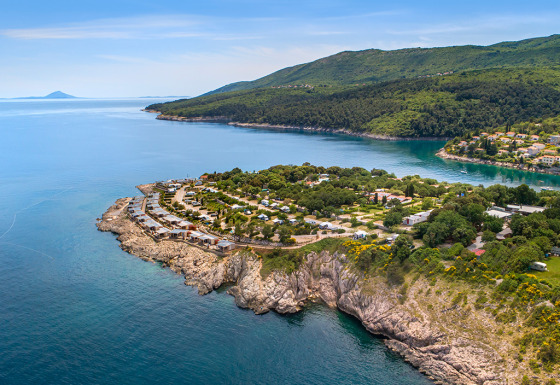 Vista aérea del camping Valamar Marina en una costa rocosa de Istria, Croacia, rodeado de vegetación.