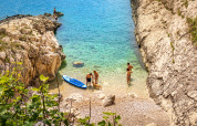 Turisti si godono la spiaggia rocciosa e l’acqua limpida al Valamar Camping Marina in Istria, Croazia.