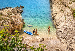 Turistas disfrutan la playa rocosa y el agua cristalina en Valamar Camping Marina, Istria, Croacia.