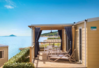 Zonnig terras met ligstoelen en eettafel bij Valamar Camping Marina met uitzicht op zee in Istrië, Kroatië.