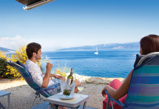 Due persone si rilassano con un bicchiere di vino osservando il mare al Valamar Camping Marina in Istria.