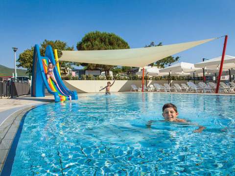 Kinderen spelen in het zwembad met glijbaan bij Valamar Camping Marina vakantiepark in Istrië, Kroatië.