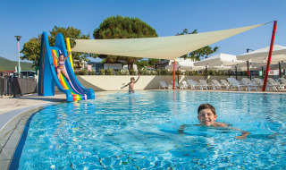Niños se divierten en la piscina con tobogán en Valamar Camping Marina, un parque vacacional en Istria, Croacia.