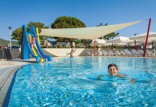 Bambini che giocano in piscina con scivolo al Valamar Camping Marina, parco vacanze in Istria, Croazia.
