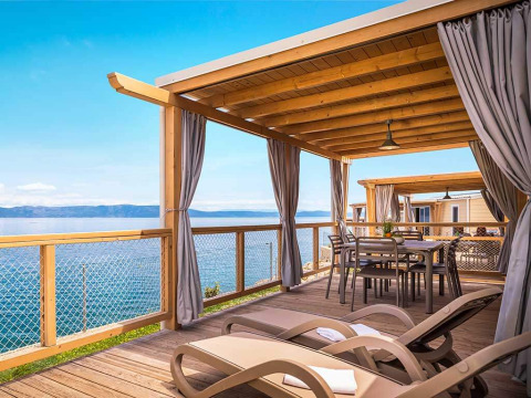 Houten terras met ligstoelen en eettafel bij Marina Home Spectacular seaview, Valamar Camping Marina, Kroatië.
