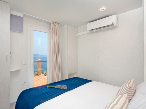 Slaapkamer met zeezicht in Marina Home, Valamar Camping Marina, Kroatië, modern ingericht met blauw beddengoed.