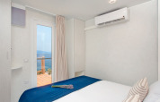 Slaapkamer met zeezicht in Marina Home bij Valamar Camping Marina, Kroatië, modern en blauw bedsprei.