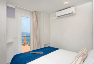 Slaapkamer met zeezicht in Marina Home, Valamar Camping Marina, Kroatië, modern ingericht met blauw beddengoed.