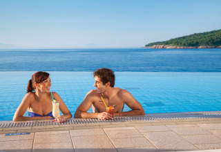 Pareja disfruta bebidas en la piscina infinita con vistas al mar en Valamar Camping Marina, Istria, Croacia.