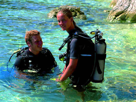 Deux personnes en équipement de plongée se tiennent dans l'eau claire à Valamar Camping Marina, Istrie, Croatie.