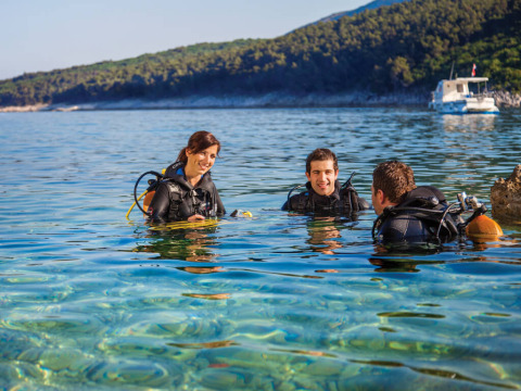 Drie duikers genieten van het heldere water bij Valamar Camping Marina in Istrië, Kroatië.