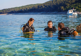Three people in diving gear enjoying the crystal clear water at Valamar Camping Marina in Istria, Croatia.