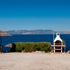 Vista al mar en Valamar Camping Marina en Istria, Croacia, con una barbacoa y sombrillas de paja en primer plano.