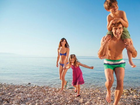 Blije familie geniet van een zonnige dag op het strand bij Valamar Camping Marina, Istrië, Kroatië.