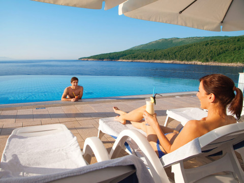 Pareja descansando junto a la piscina en Valamar Camping Marina con vistas al mar en Istria, Croacia.