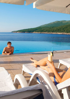 Pareja descansando junto a la piscina en Valamar Camping Marina con vistas al mar en Istria, Croacia.