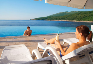 Couple se relaxant au bord de la piscine à Valamar Camping Marina, avec vue sur mer en Istrie, Croatie.