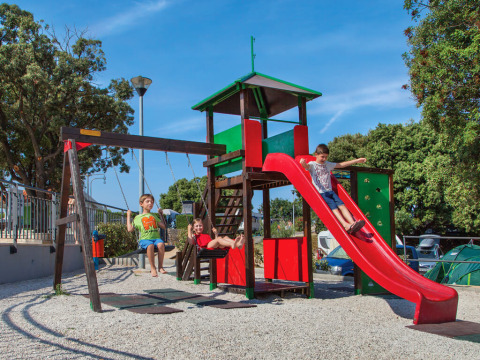 Kinderen spelen op een speelplaats met glijbaan en schommels bij Valamar Camping Marina, Istrië, Kroatië.