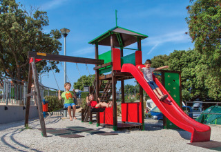 Kinderen spelen op een speelplaats met glijbaan en schommels bij Valamar Camping Marina, Istrië, Kroatië.