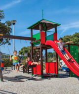 Niños juegan en un parque infantil con tobogán y columpios en Valamar Camping Marina, Istria, Croacia.