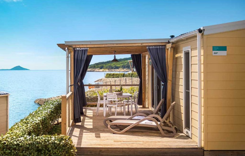 Marina Home Seaside cabin met terras, ligstoelen en uitzicht op zee onder een heldere blauwe lucht