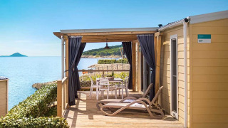Marina Home Seaside cabin met terras, ligstoelen en uitzicht op zee onder een heldere blauwe lucht