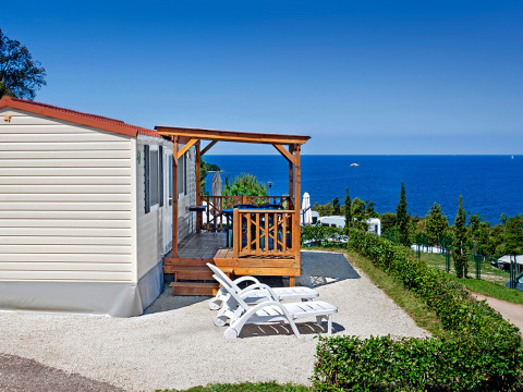 Orsera Home lodge featuring a wooden terrace, two loungers, and a panoramic sea view on a sunny day.