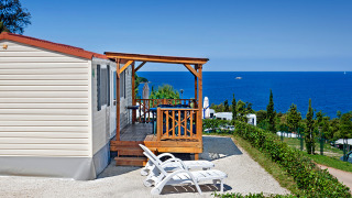 Orsera Home lodge met houten terras, twee ligstoelen en schitterend uitzicht op de zee en blauwe lucht.