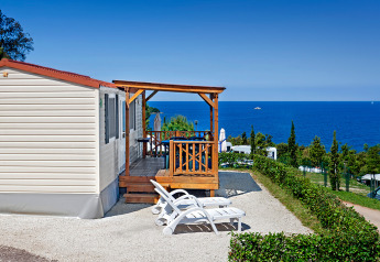 Orsera Home lodge featuring a wooden terrace, two loungers, and a panoramic sea view on a sunny day.